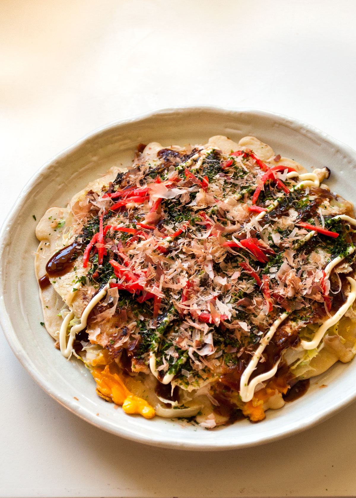 Okonomiyaki is the famous Japanese savory pancake that is usually cooked at the dining table so you can customize it to your taste.