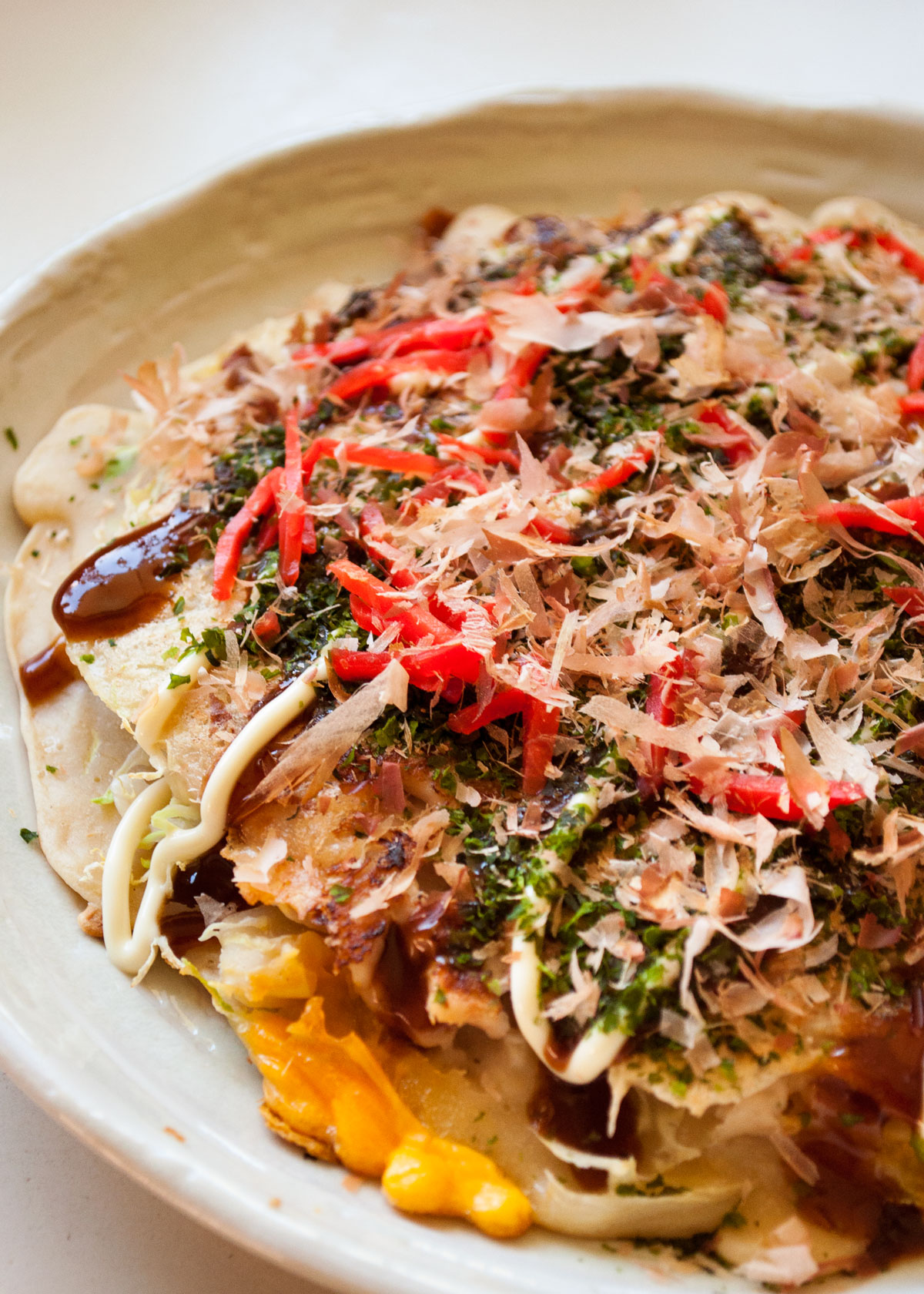 Okonomiyaki is the famous Japanese savory pancake that is usually cooked at the dining table so you can customize it to your taste.