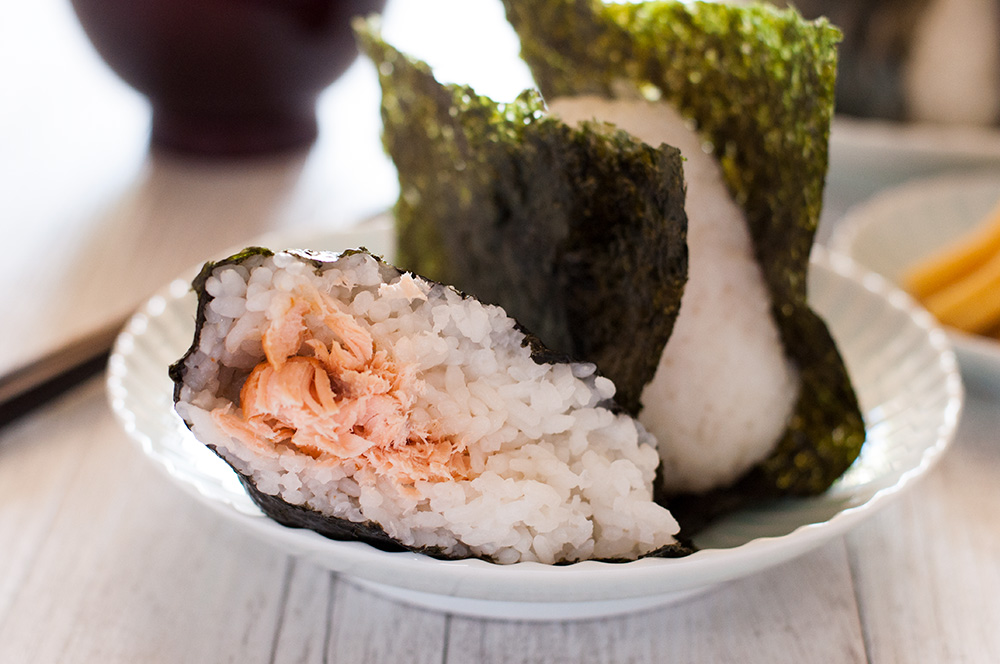 Nothing is more comforting than onigiri (おにぎり, Japanese rice ball) wrapped in yaki nori (焼き海苔, roasted seaweed sheet) with salted grilled salmon inside the rice! It’s such a simple food but it is so yummy you can’t stop eating. Instead of salmon or other popular protein, you can add pickled vegetables or pickled salty plum to make it vegetarian.
