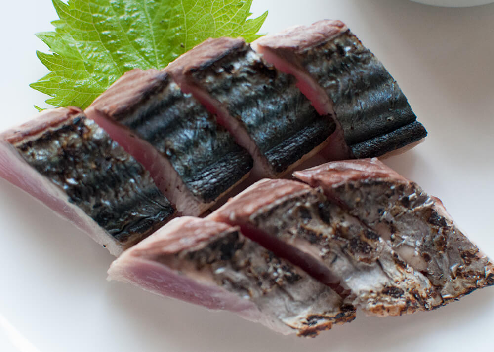 Bonito Tataki (Seared Bonito) is the representative sashimi dish of Kōchi prefecture. When the bonito skin is seared and charred, it gives an appetising aroma to the sashimi. Slice the fillets thicker than usual sashimi slices and eat them with ponzu dressing.