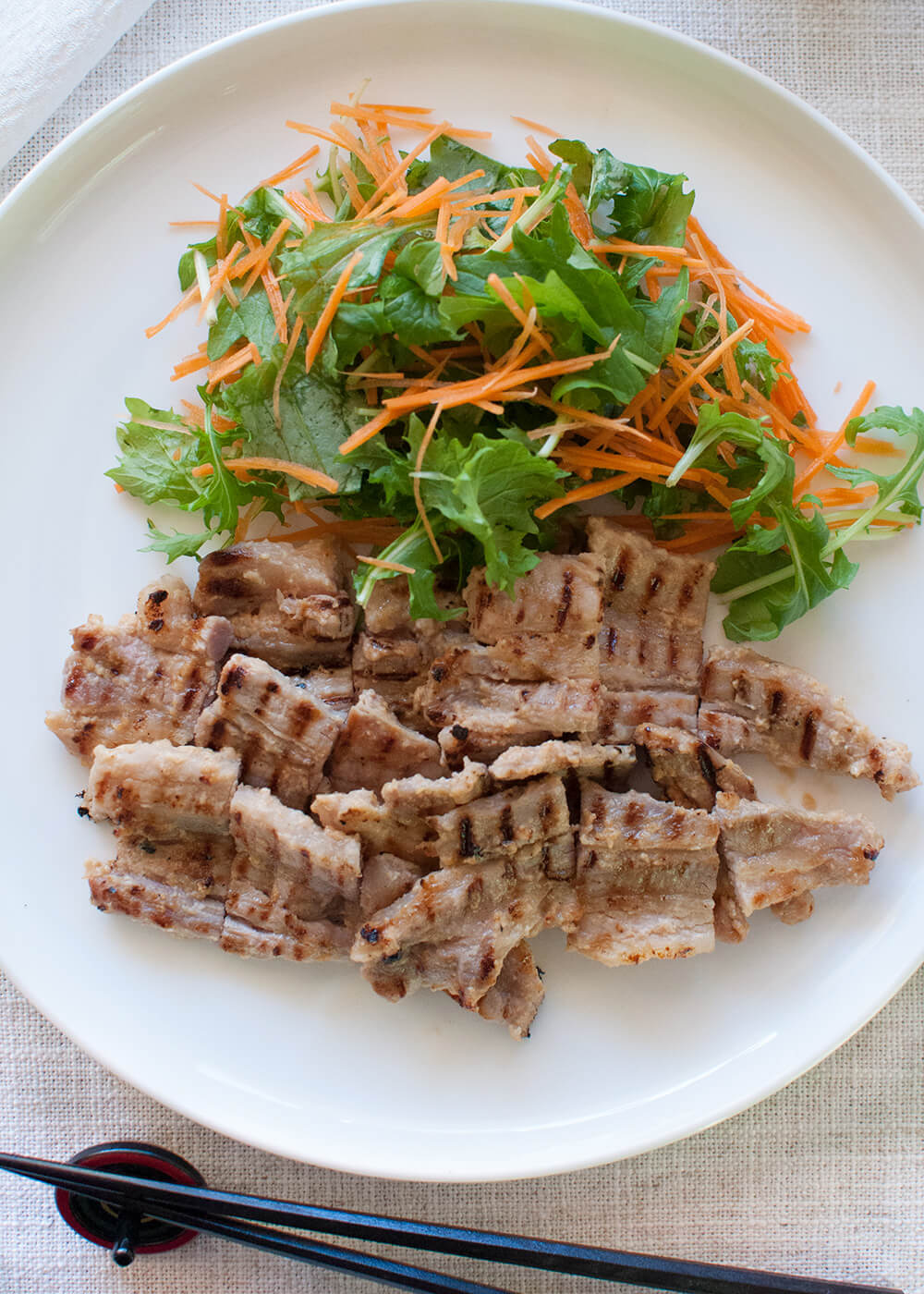 Pork Kasuzuke cooked on a griddle pan look appertaining with burnt lines. Served with mizuna and carrot salad.