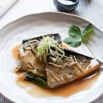 Simmered mackerel in miso served on a plate topped with julienned shallots (scallions)