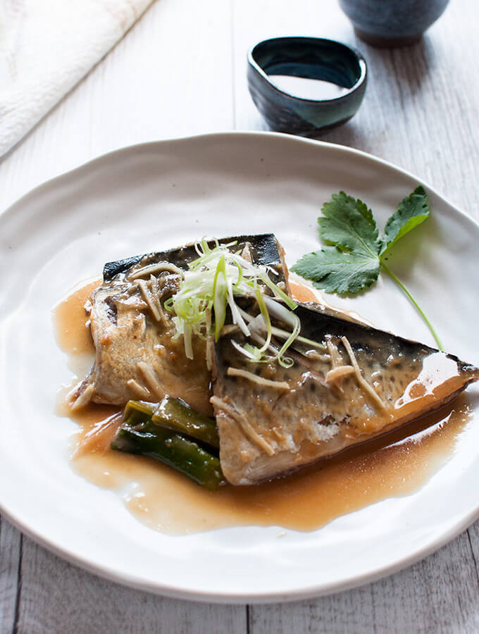 Simmered mackerel in miso served on a plate topped with julienned shallots (scallions)