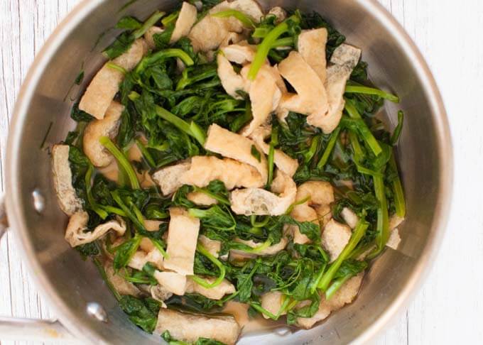 Snow pea leaves and aburrage cooked in a pot.