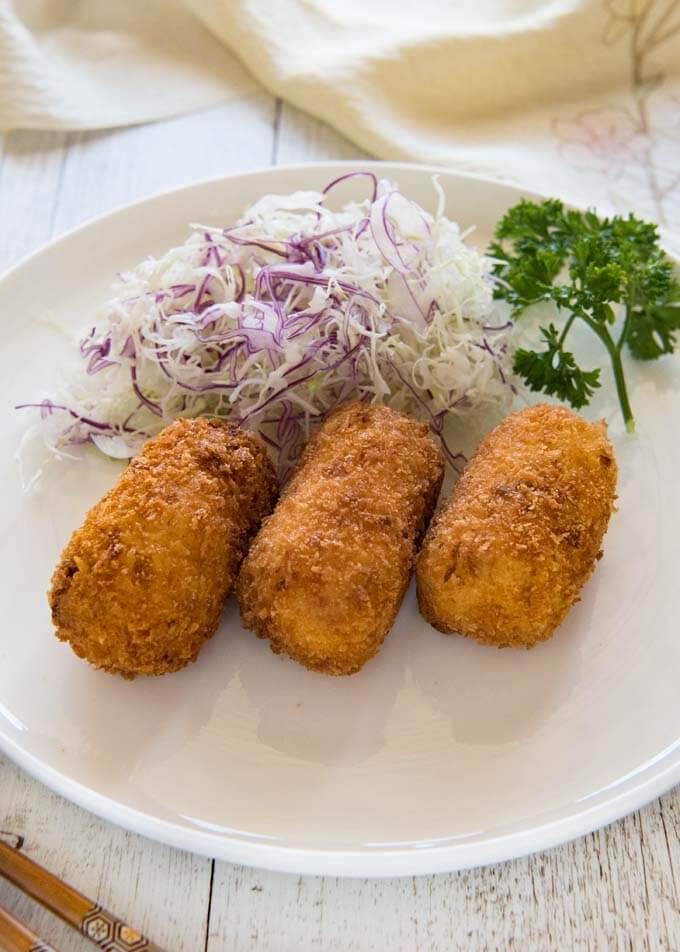 Creamy Shrimp Croquettes with shredded cabbage on a plate.