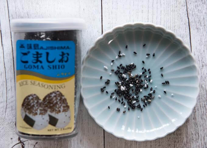 Gomashio - roasted sesame and salt in a container and on a plate.