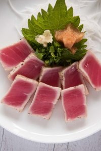 Serving Tuna Tataki with condiments - grated ginger, chopped shallots and momiji oroshi (grated daikon with chilli) on a perilla leaf - before pouring Ponzu Dressing.