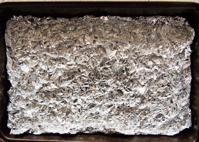 Scrunched aluminium foil placed on a grilling tray.