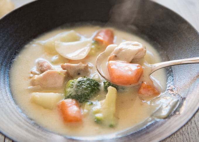 Spooning the stew from the bowl.