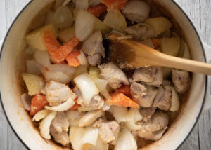 After mixing the flour into the sautéed meat and vegetables.