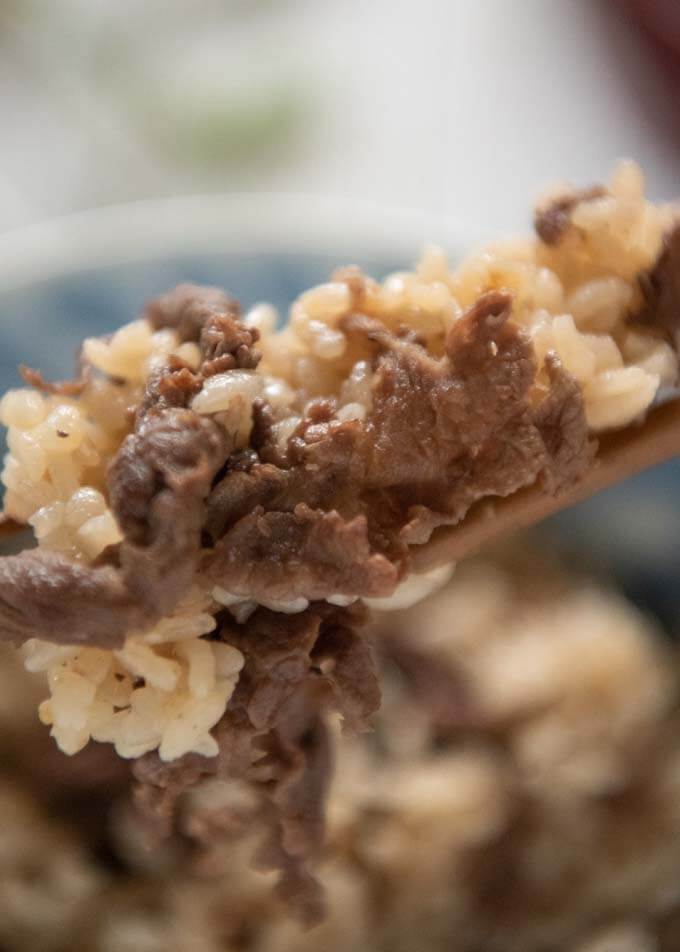 Zoomed-in photo of the rice with a piece of beef picked up with chopsticks.