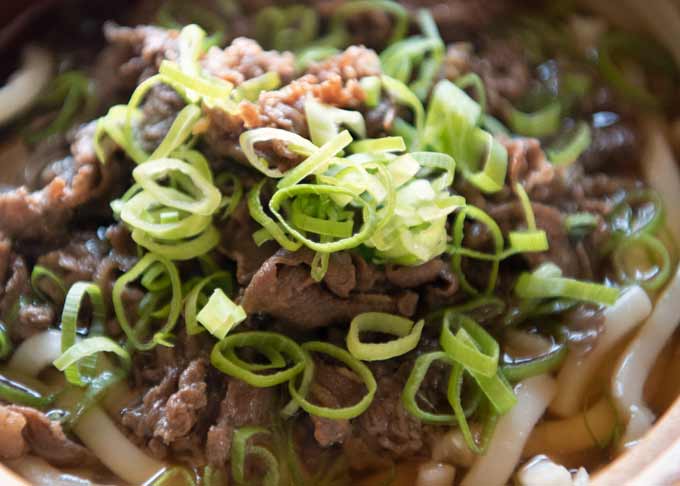 Zoomed-in photo of beef topping with fresh greed chopped shallots.