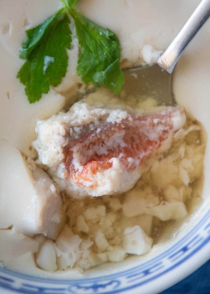 Scooping a piece of fish with a spoon in the Fish Chawanmushi.