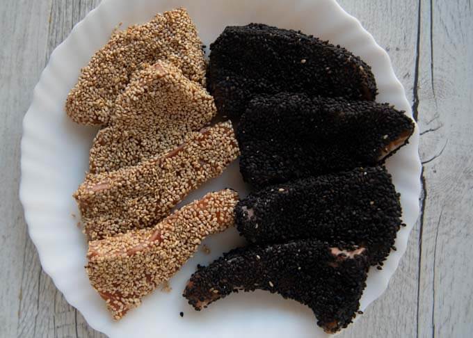 Some salmon pieces coated in white sesame seeds, some in black sesame seeds.