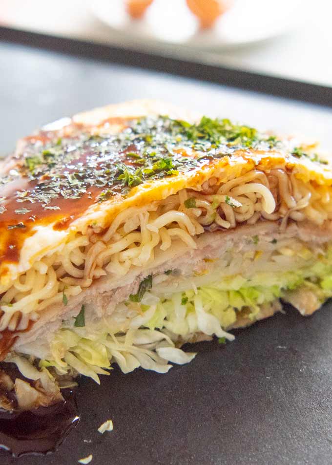 Zoomed-in photo of okonomiyaki cut in half, showing the layers of ingredients.