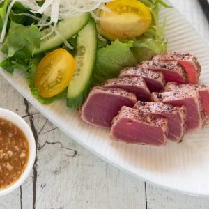 Hero shot of Tuna Sashimi Salad with Garlic Sesame Dressing on the side.
