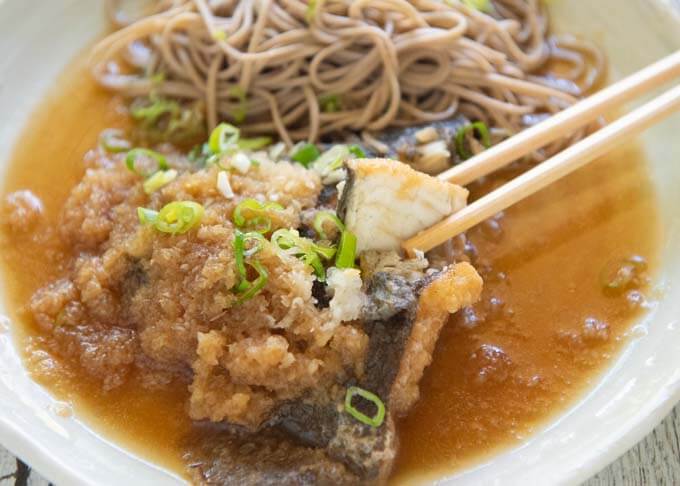 Zoomed-in photo of Flounder Mizore-ni (Simmered Flounder in Grated Daikon), picking up a fish piece with chopsticks.