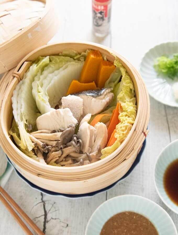 Hero shot of Steamed Chicken and Fish with Vegetables served with two dipping sauces.