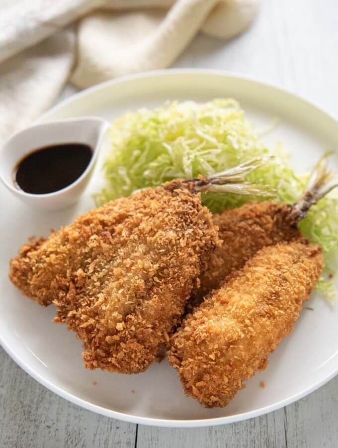Hero shot of Deep-fried Horse Mackerel on a plate servedwith shredded lettuce and sauce.
