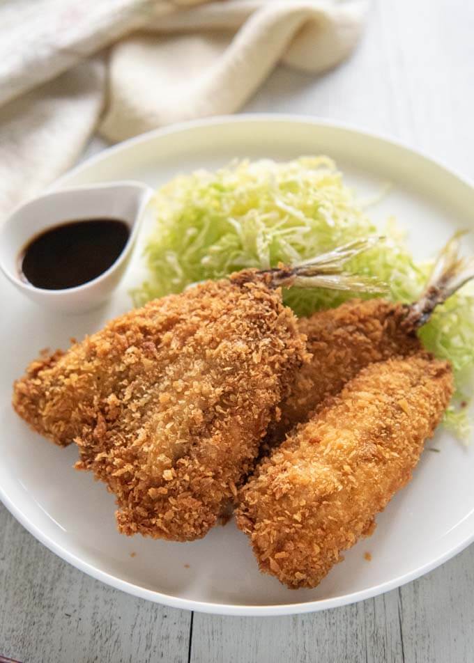 Hero shot of Deep-fried Horse Mackerel on a plate servedwith shredded lettuce and sauce.