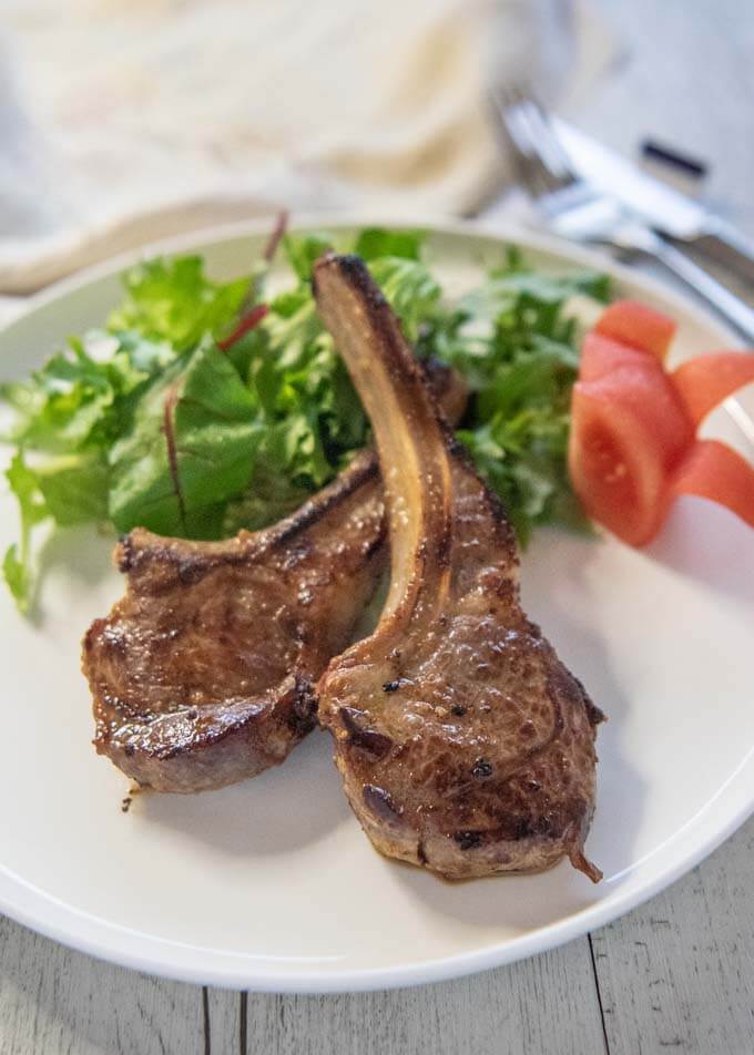 Hero shot of Pan-Fried Lamb Chops with Miso Marinade served with salad and tomato wedges.