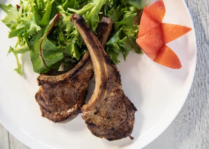 Top-down photo of Pan-Fried Lamb Chops with Miso Marinade served with salad and tomato wedges.