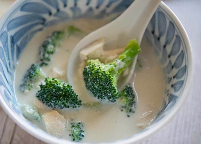 Scooping broccoli and tofu from the bowl of Broccoli and Soy Milk Soup.