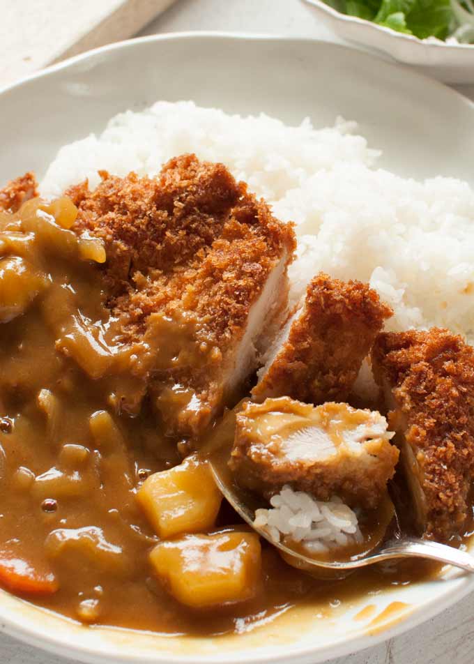 Scooping Katsu and curry with rice using a spoon.