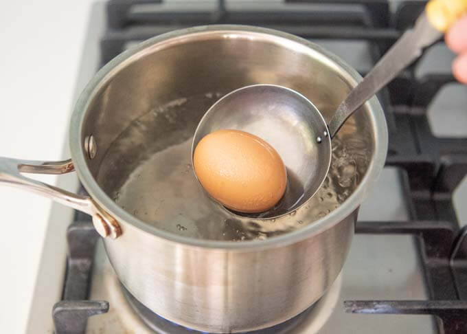 Use a ladle to gently put a chilled egg in the boiling water.