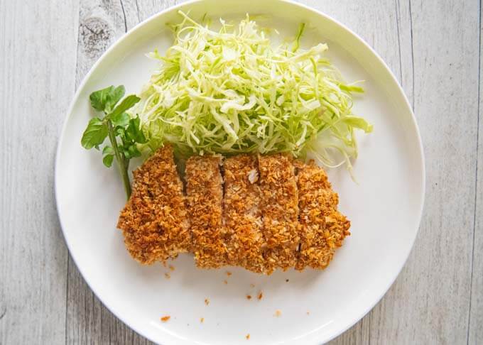 Top-down photo of Oven Baked Tonkatsu with shredded cabbage on side.