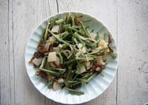 Drained pre-boiled mountain vegetables on a plate.