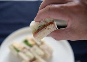 Zoomed-in photo of a piece of ham sandwich picked up with fingers.