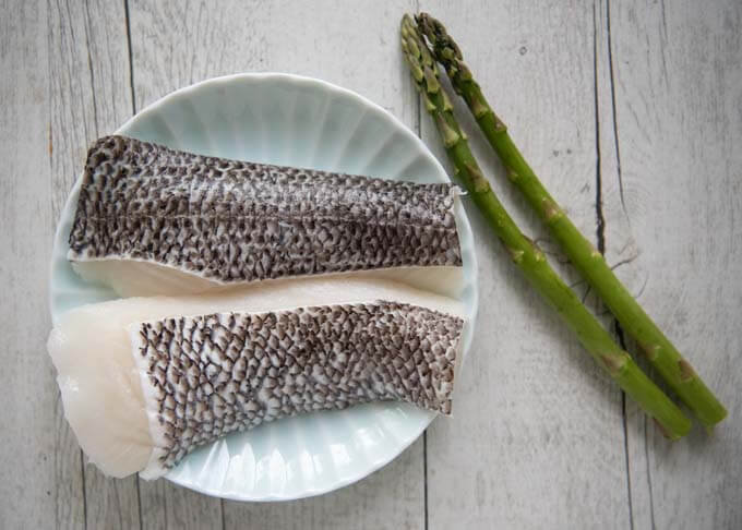 The fish fillets to be marinated and 2 spears of asparagus for garnish.