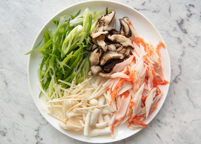 Vegetables and imitation crab meat cut into small pieces.