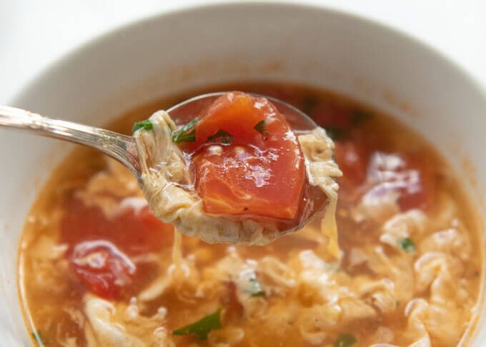Scooping soup in a spoon.