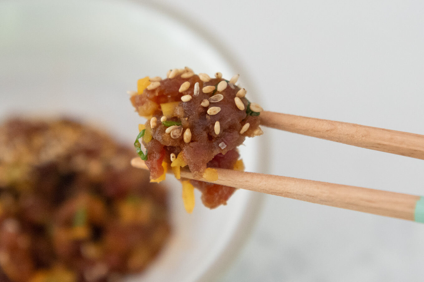 Picking up some Spicy Tuna Tatare with Pickled Daikon with chopsticks.