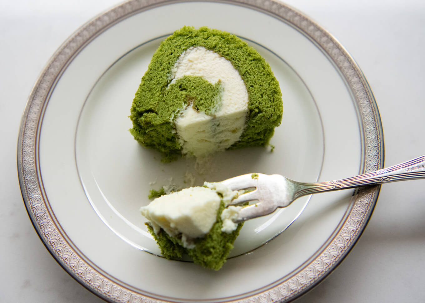 Taking a bite-size piece from a slice of Matcha Roll Cake.
