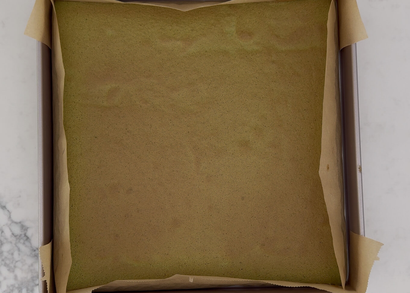 Matcha sponge cake just out of the oven. The surface is lightly browned.