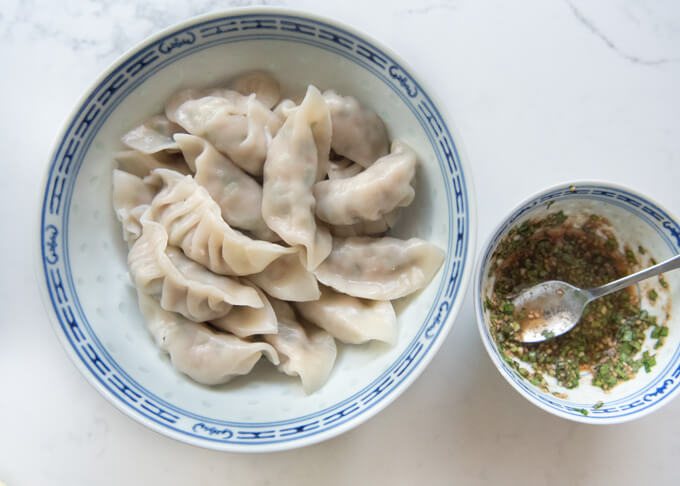 Boiled gyoza in a large bowl with the sauce.
