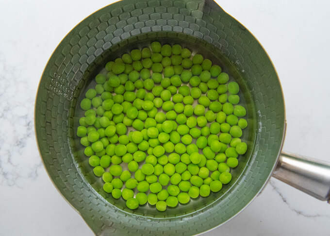 Leaving cooked peas in the cooking liquid to keep them stay plump.
